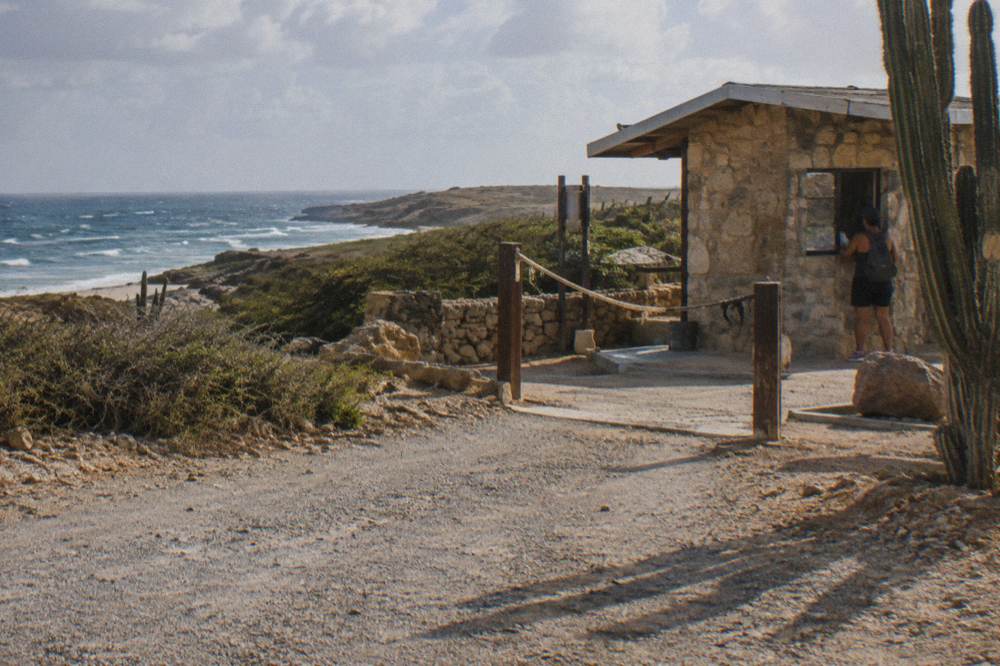 A dry park landscape of cacti and limestone with a distant stone checkpoint structure