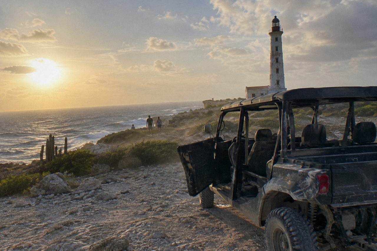 A side-by-side UTV parked on a rocky dirt trail above Aruba's windswept north coast
