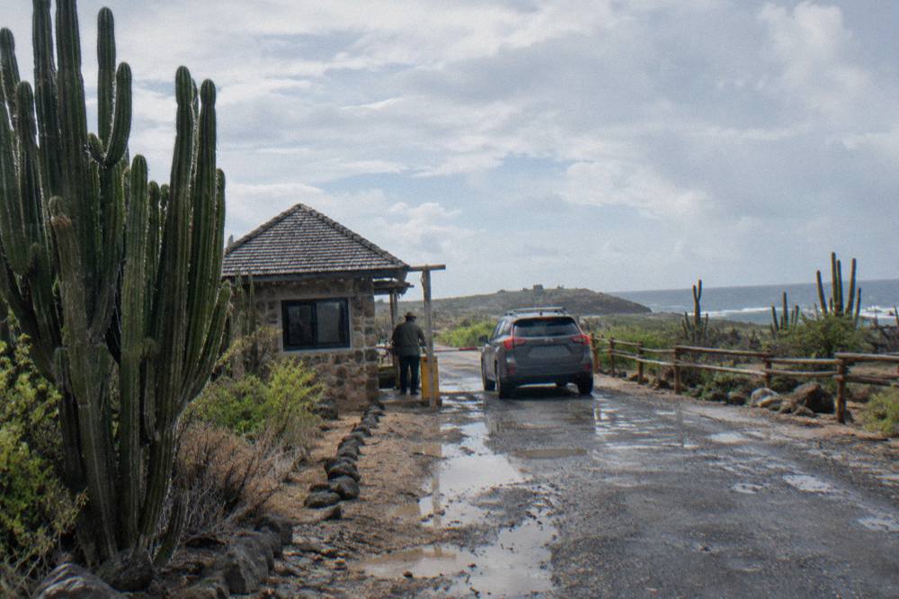 Entrance booth at a national park gate with a signboard and a dry rocky landscape behind it