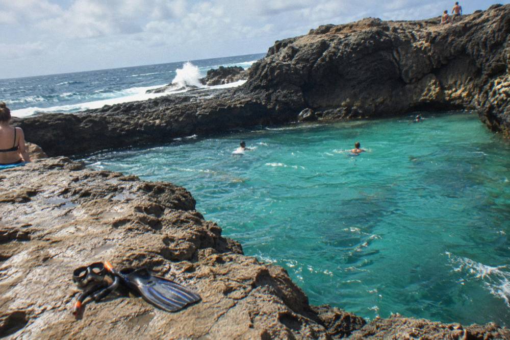 Turquoise water filling a rocky coastal basin with dark stone walls