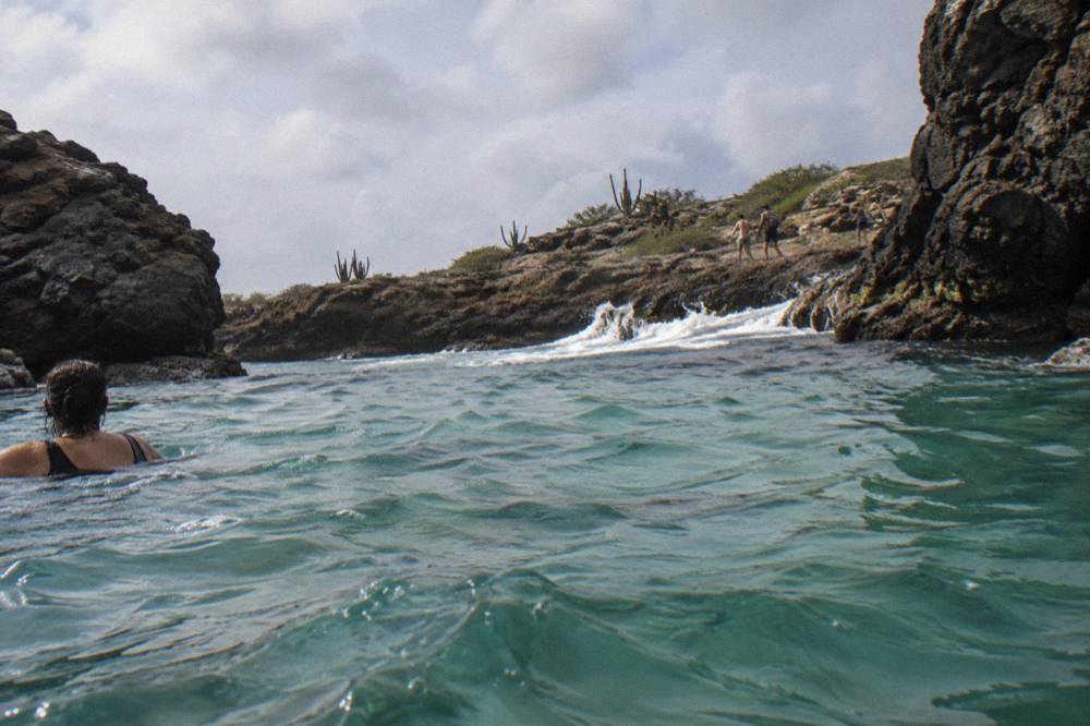 Turquoise water filling a natural rock basin along a rugged shore