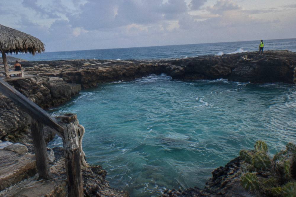 Turquoise water filling a volcanic rock basin with the open ocean beyond