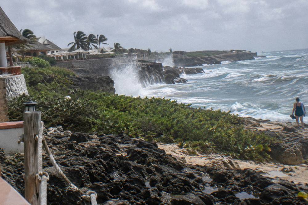 Rocky coastal terrain with waves striking dark stone formations under open sky