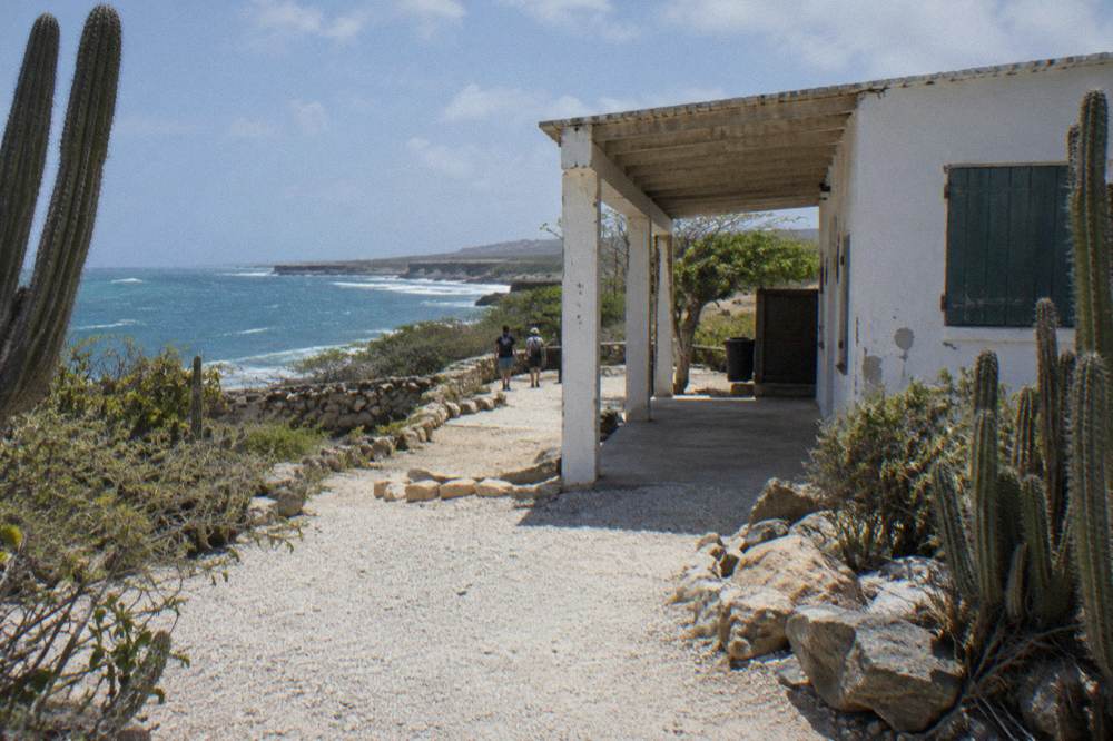 A small park entrance building with a covered walkway surrounded by dry scrubland and cactus