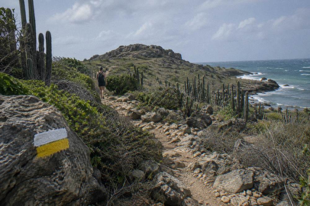 Marked hiking trail crossing dry scrubland toward a rocky hilltop inside the park