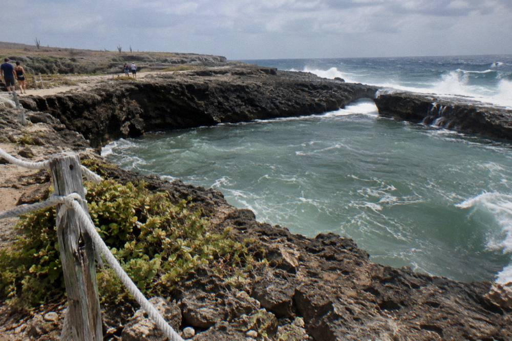 Volcanic rock basin of the Natural Pool with waves breaking on the outer rim under an open sky