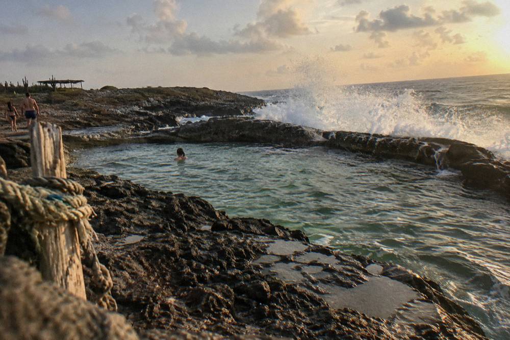 Volcanic rock formations forming a natural pool basin along a rugged coastline
