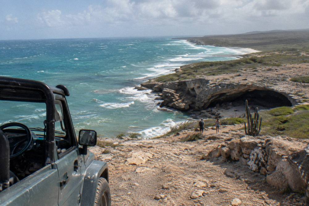 Open air jeep parked on a rocky plateau overlooking the coastline