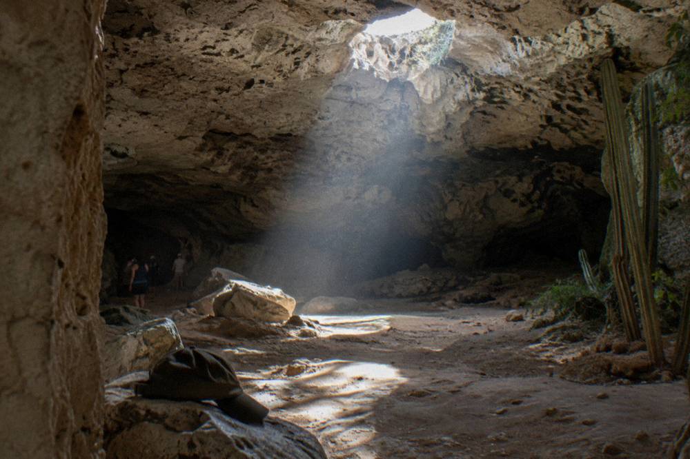 A limestone cave opening with sunlight entering through a hole in the rock ceiling