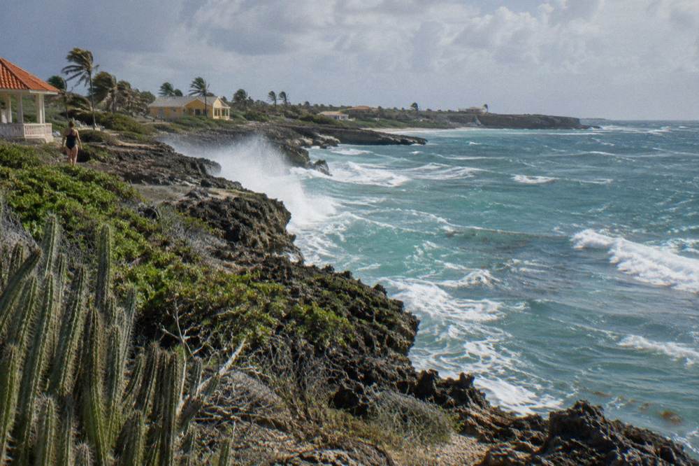 A rocky shoreline on a windy coast with white waves crashing against dark stone