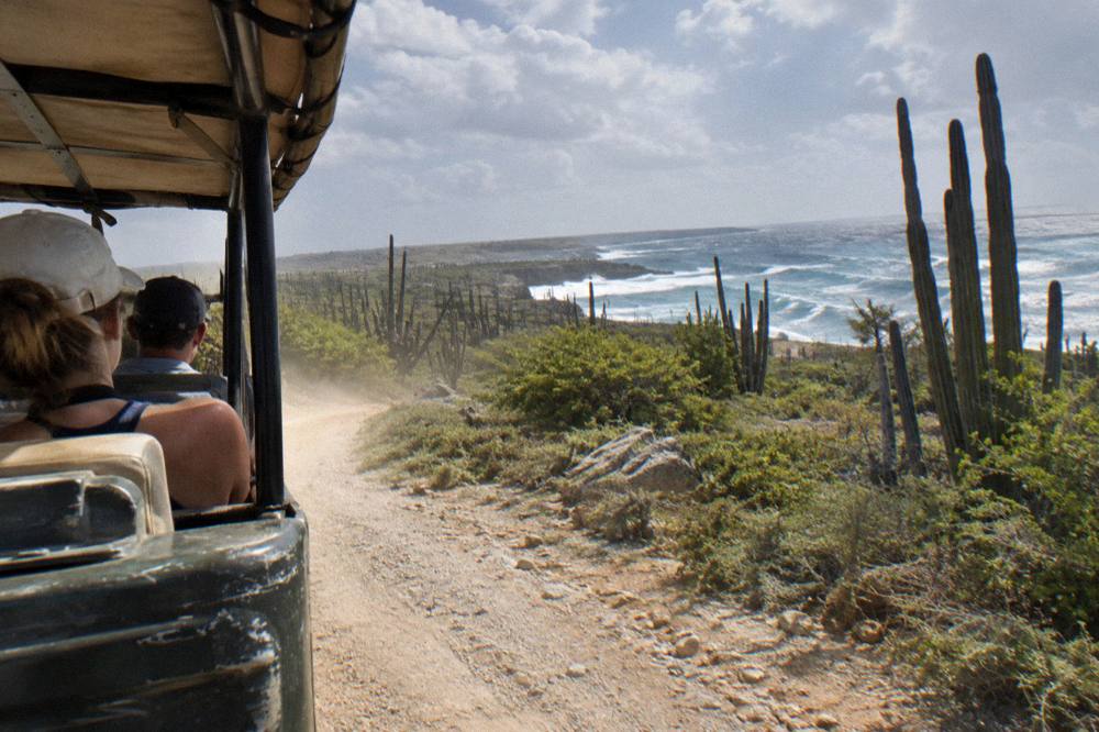 An open-air four-wheel-drive vehicle traveling on a rocky trail through dry landscape