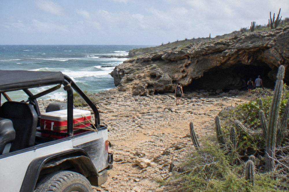 Open-air jeep parked on a rocky plateau near coastal rock formations