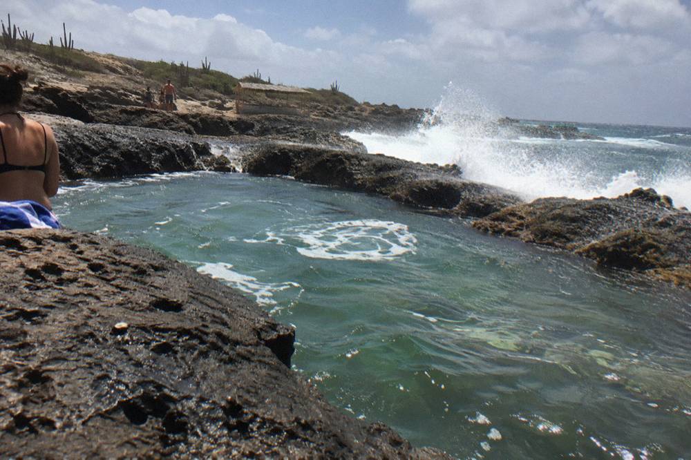 Volcanic rock basin beside crashing ocean surf along a rugged shoreline