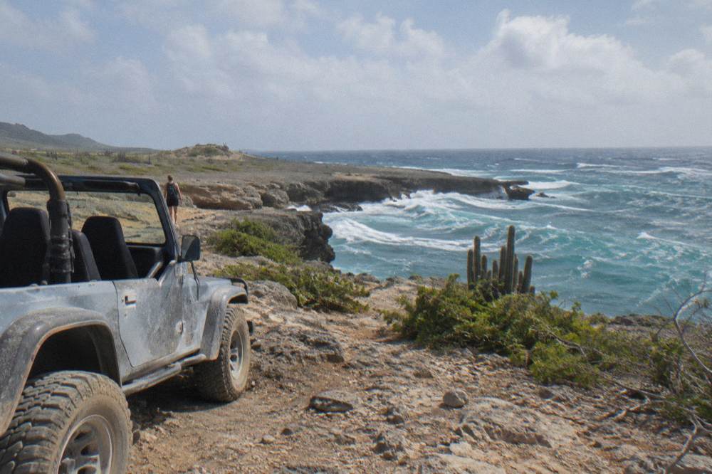 Open-air four-wheel-drive vehicle parked on a rocky coastal plateau