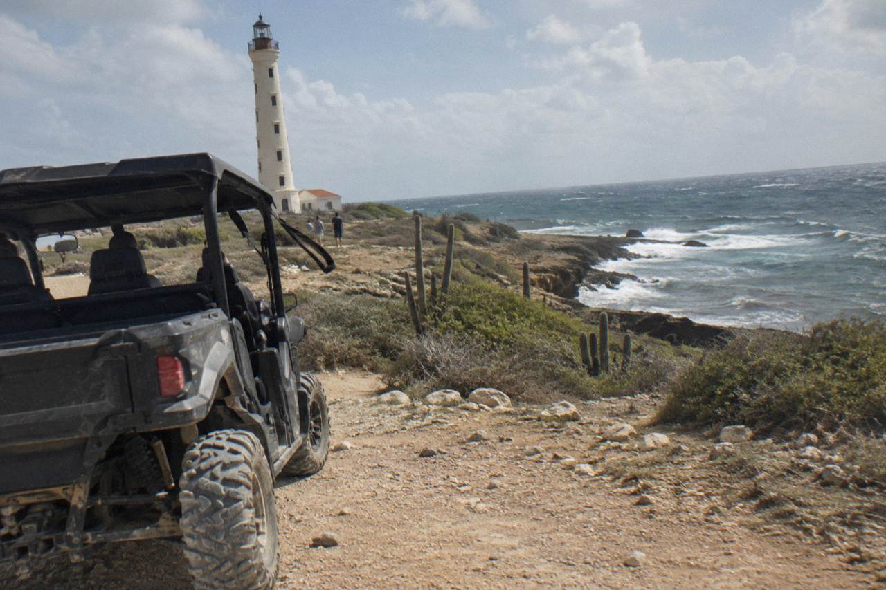 A four seat UTV parked on a rugged dirt track along Aruba's rocky north coast shoreline