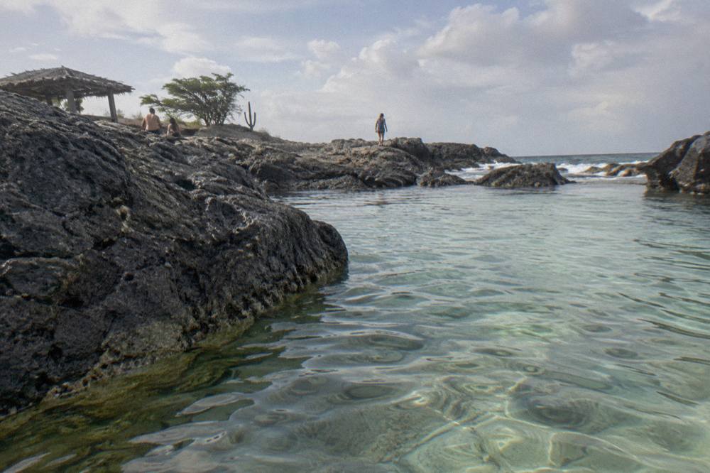 A calm volcanic rock pool in early morning light with clear shallow water