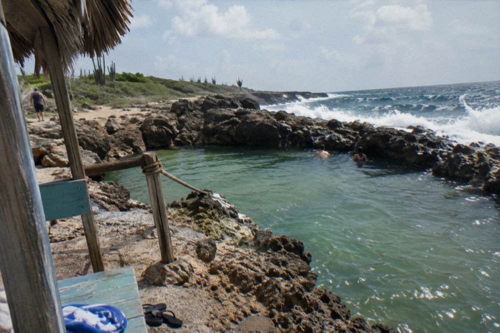 A natural rock pool enclosed by dark volcanic stone near a breaking sea