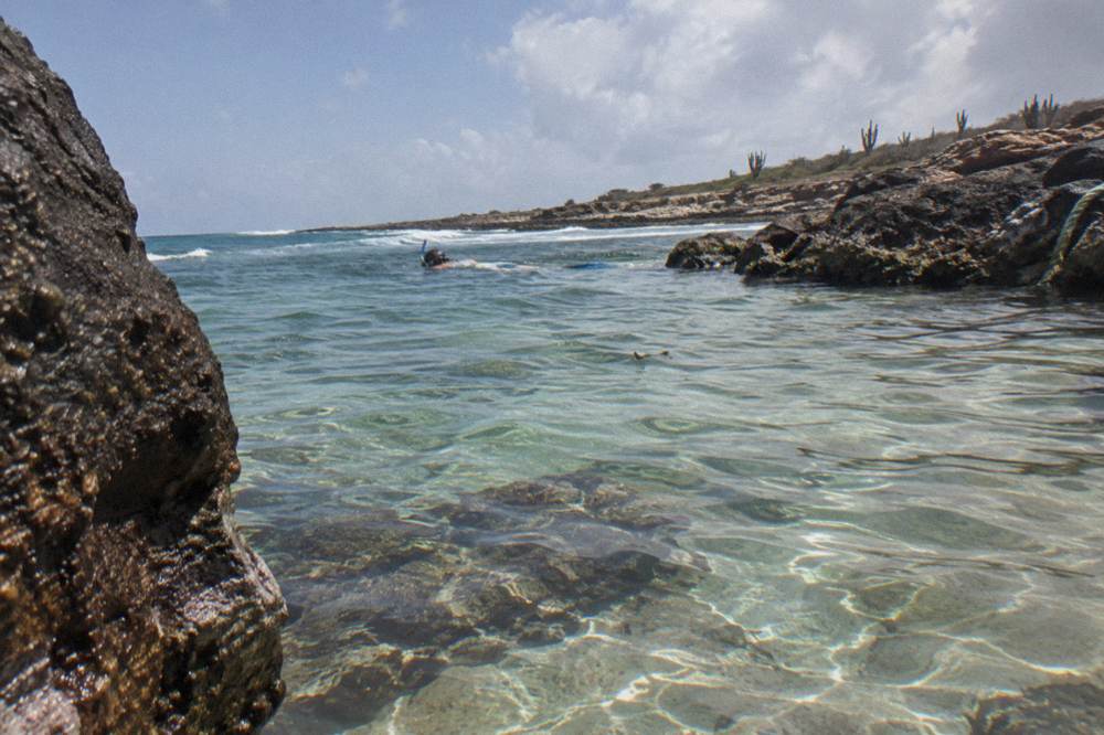 Snorkeler floating in a calm rock pool with clear shallow water