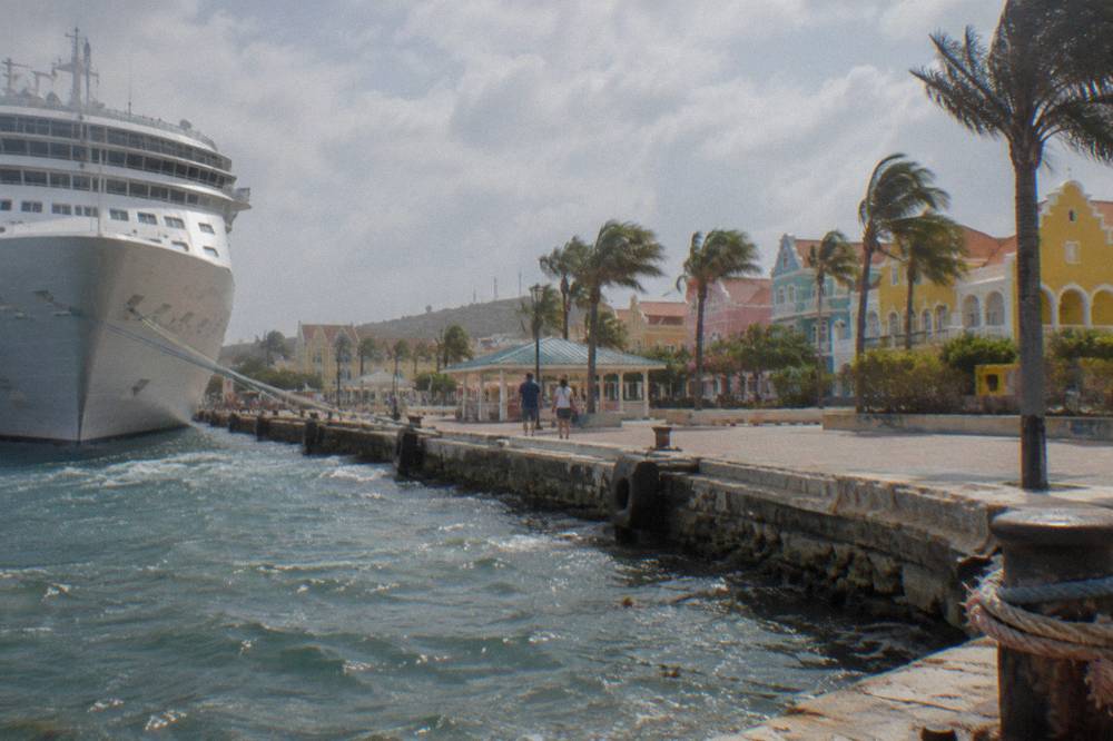 Cruise ship docked at a waterfront terminal with tour vehicles parked nearby