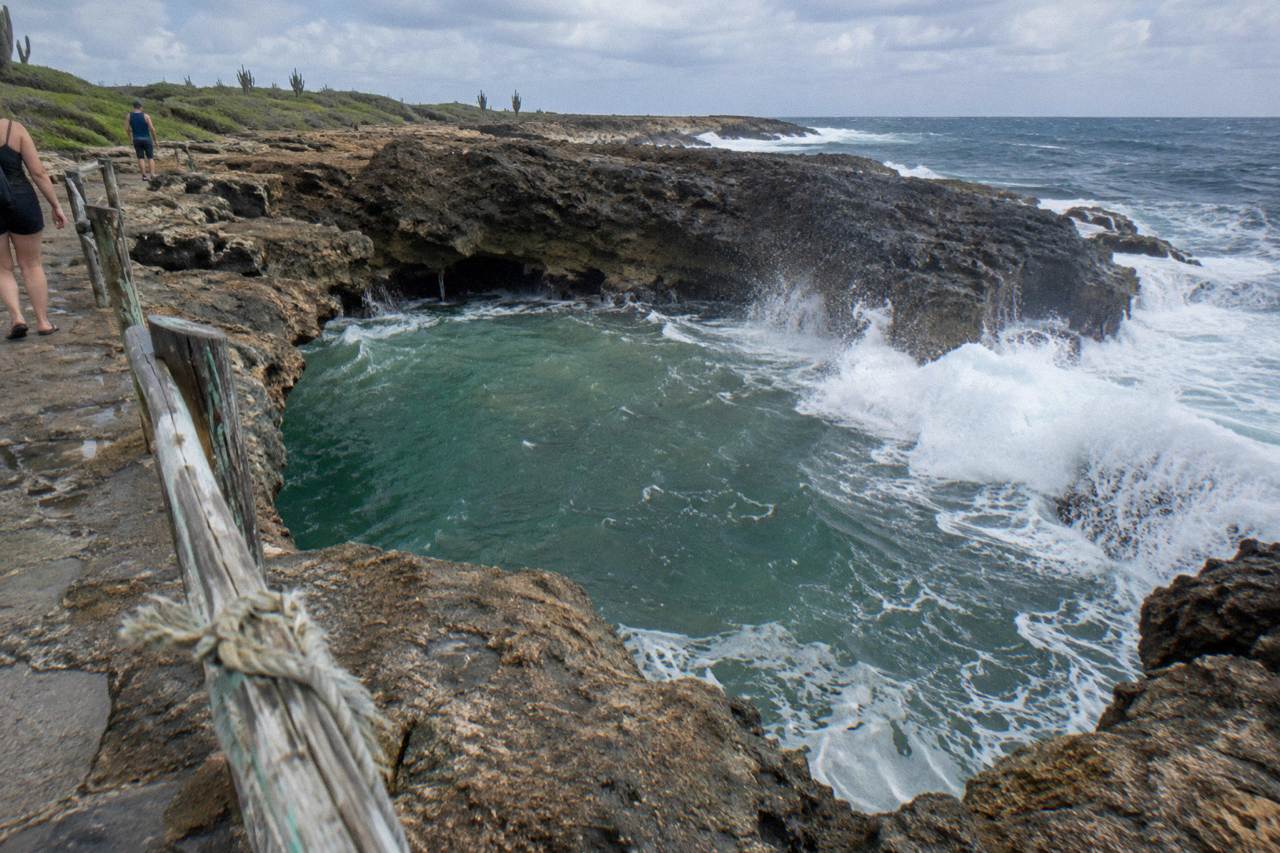 Rocky volcanic coastline with waves breaking against a natural pool basin