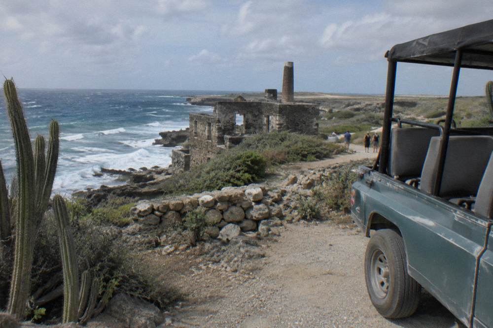 Tour jeep parked on a dirt track above the rugged north shore of Aruba