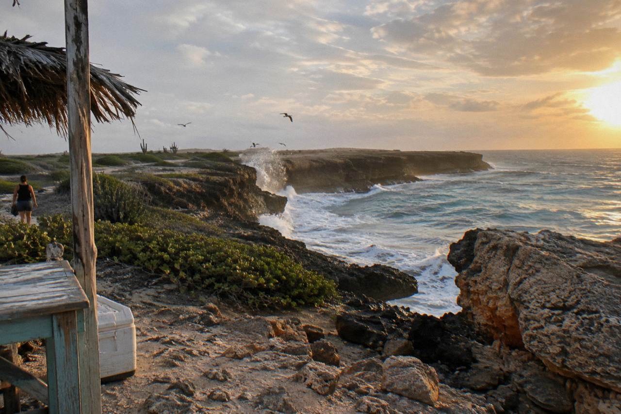 Rocky limestone coast of north-east Aruba with waves breaking against dark cliffs at sunrise