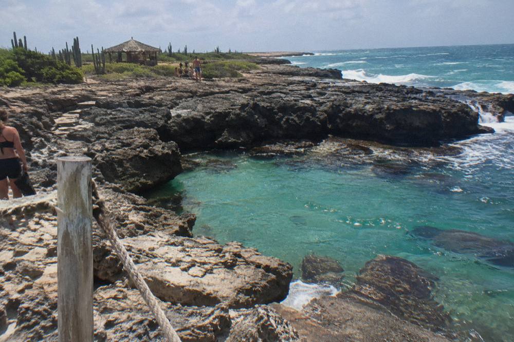 Turquoise water pooling among dark volcanic rocks on a dry coastal plain