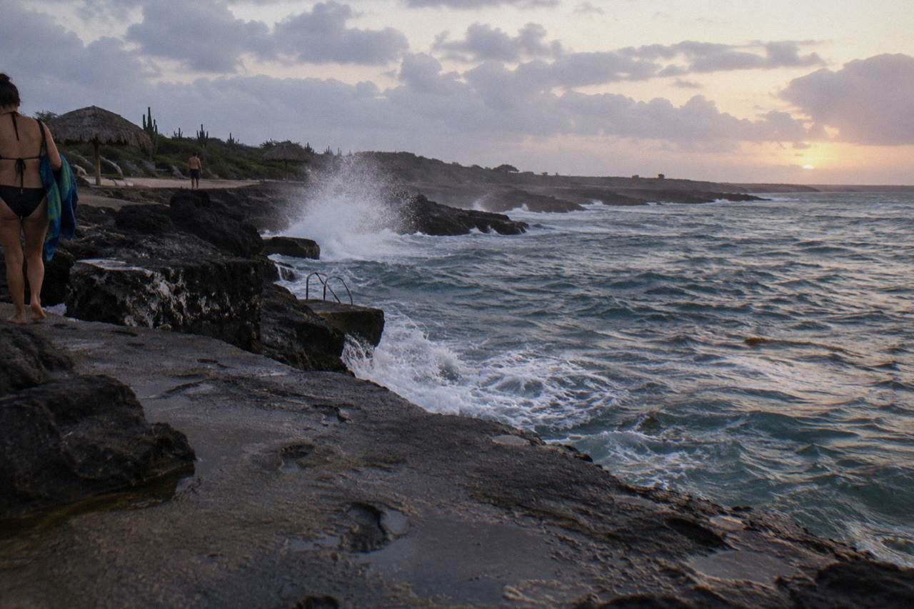 Rocky volcanic coastline of Aruba with waves breaking against dark stone
