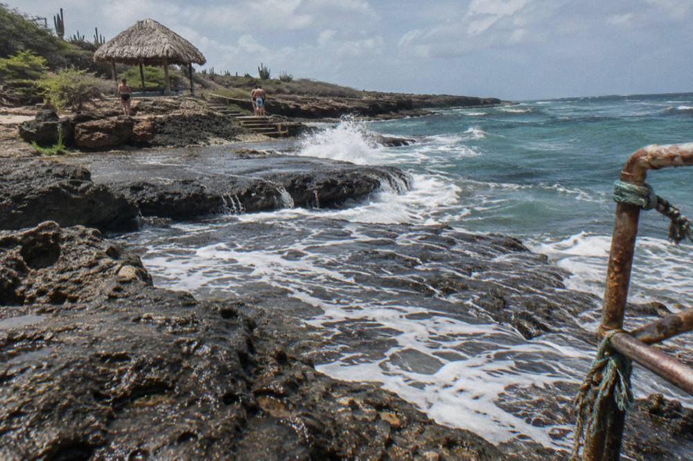 Rough volcanic shoreline with white waves crashing against dark rock