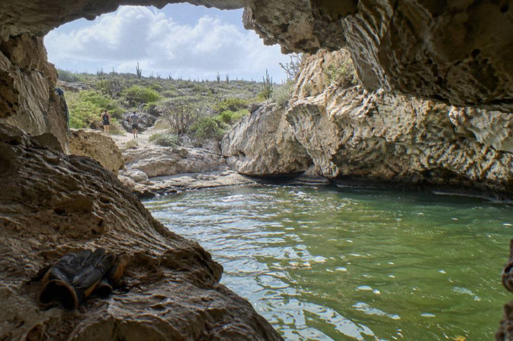 Still green water inside a rock bowl with dark jagged stone rising around it