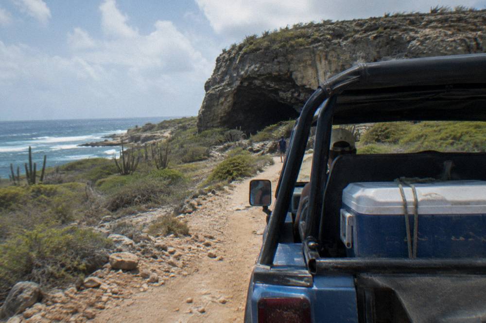 Open-sided four wheel drive vehicle on a rocky dirt track through dry scrubland