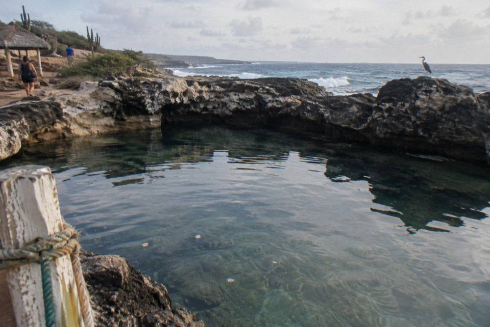 Calm clear water filling a rock basin with dark volcanic walls