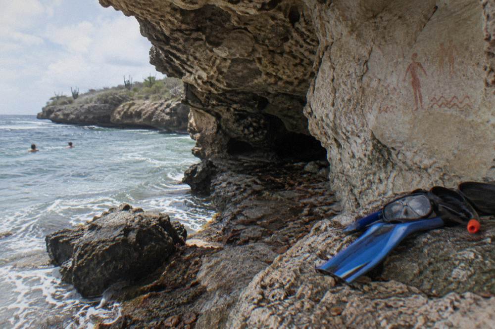 Snorkel mask and fins resting on a rock ledge beside clear water
