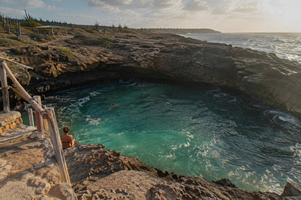 Turquoise water filling a volcanic rock basin surrounded by dark stone terraces