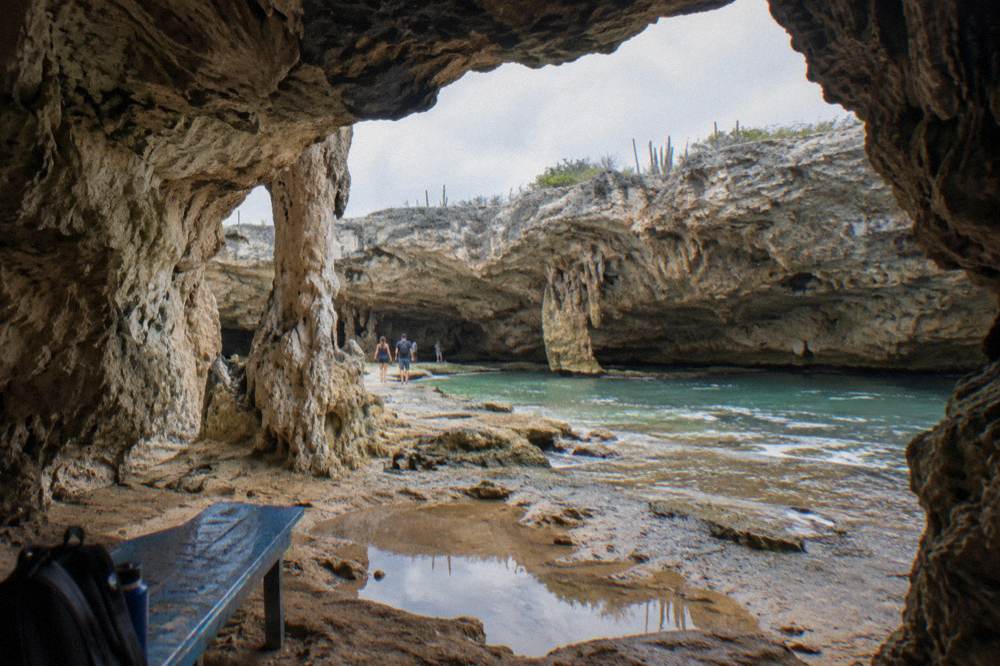 A limestone cave entrance opening into a wide sunlit cavern