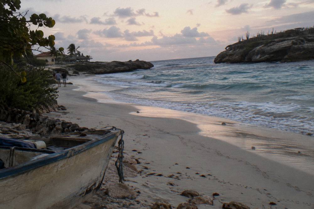 Sunrise light over a calm rocky shoreline with gentle surf