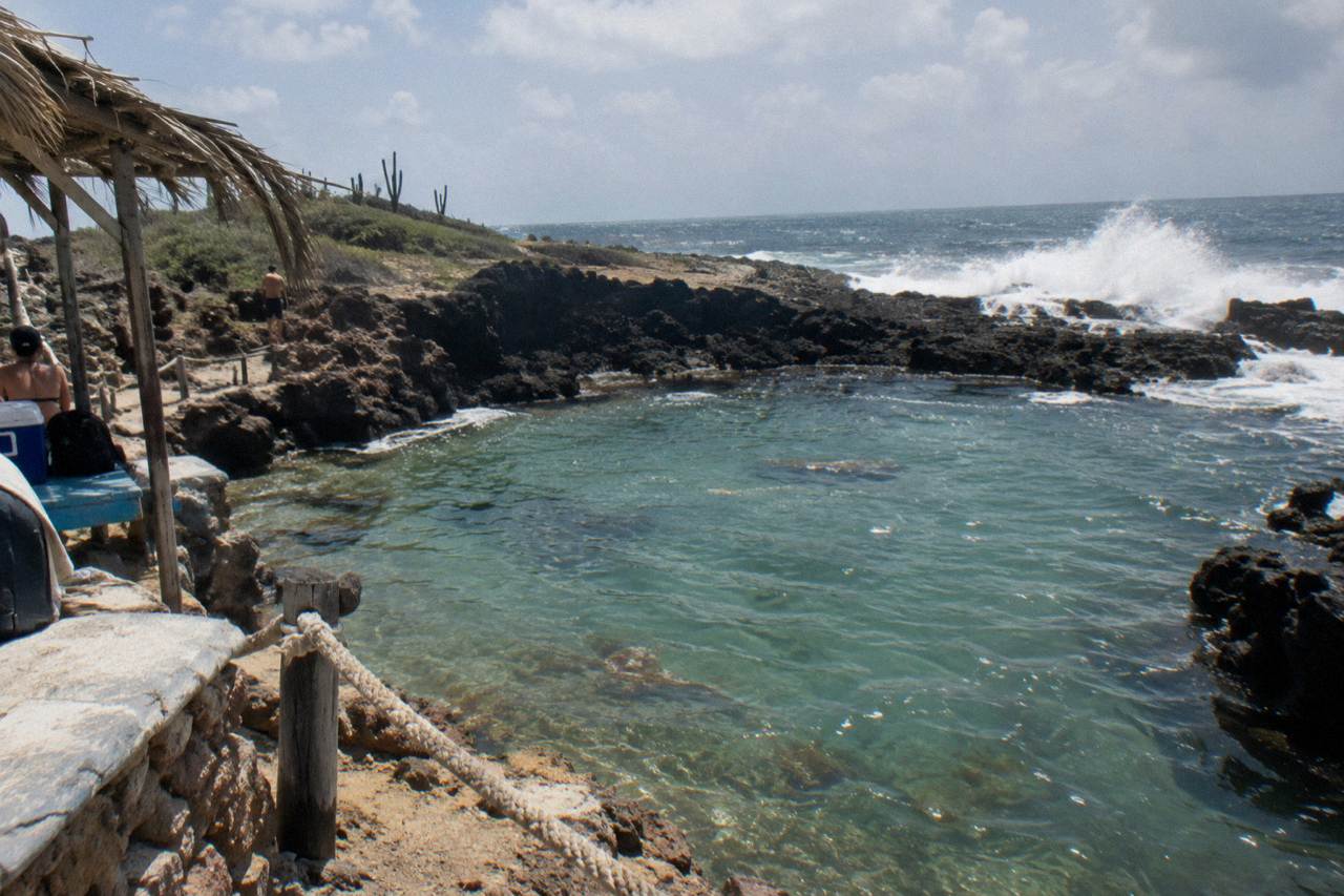 Rugged volcanic coastline with waves breaking against dark rocks near a sheltered pool