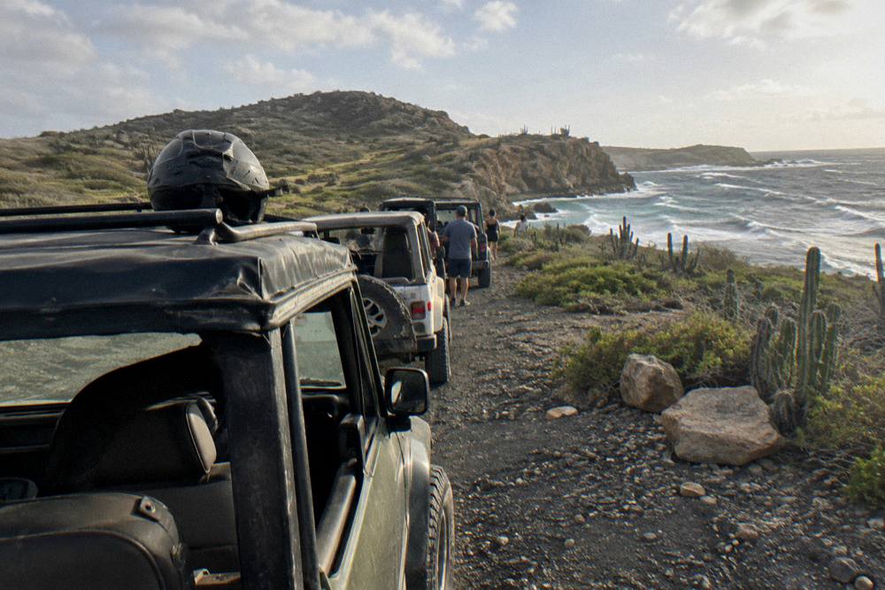 Off-road vehicles lined up at a trailhead with rocky hills in the background