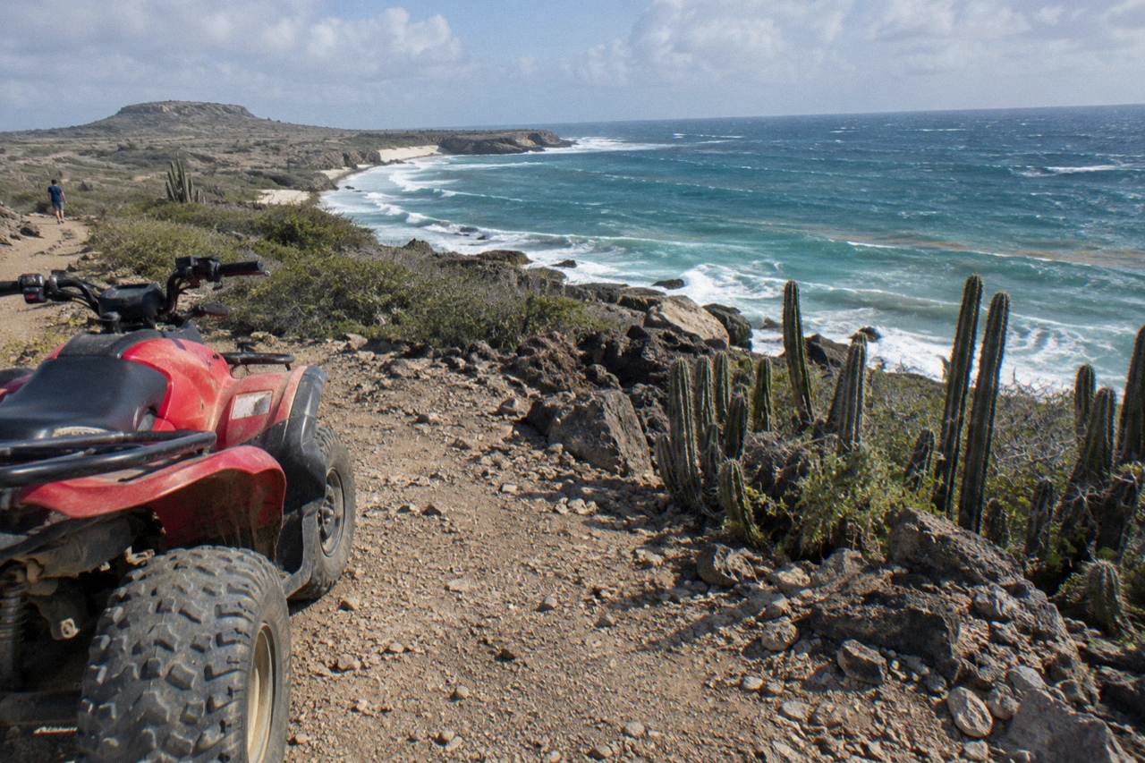 An off-road vehicle parked on a rocky desert trail overlooking the sea